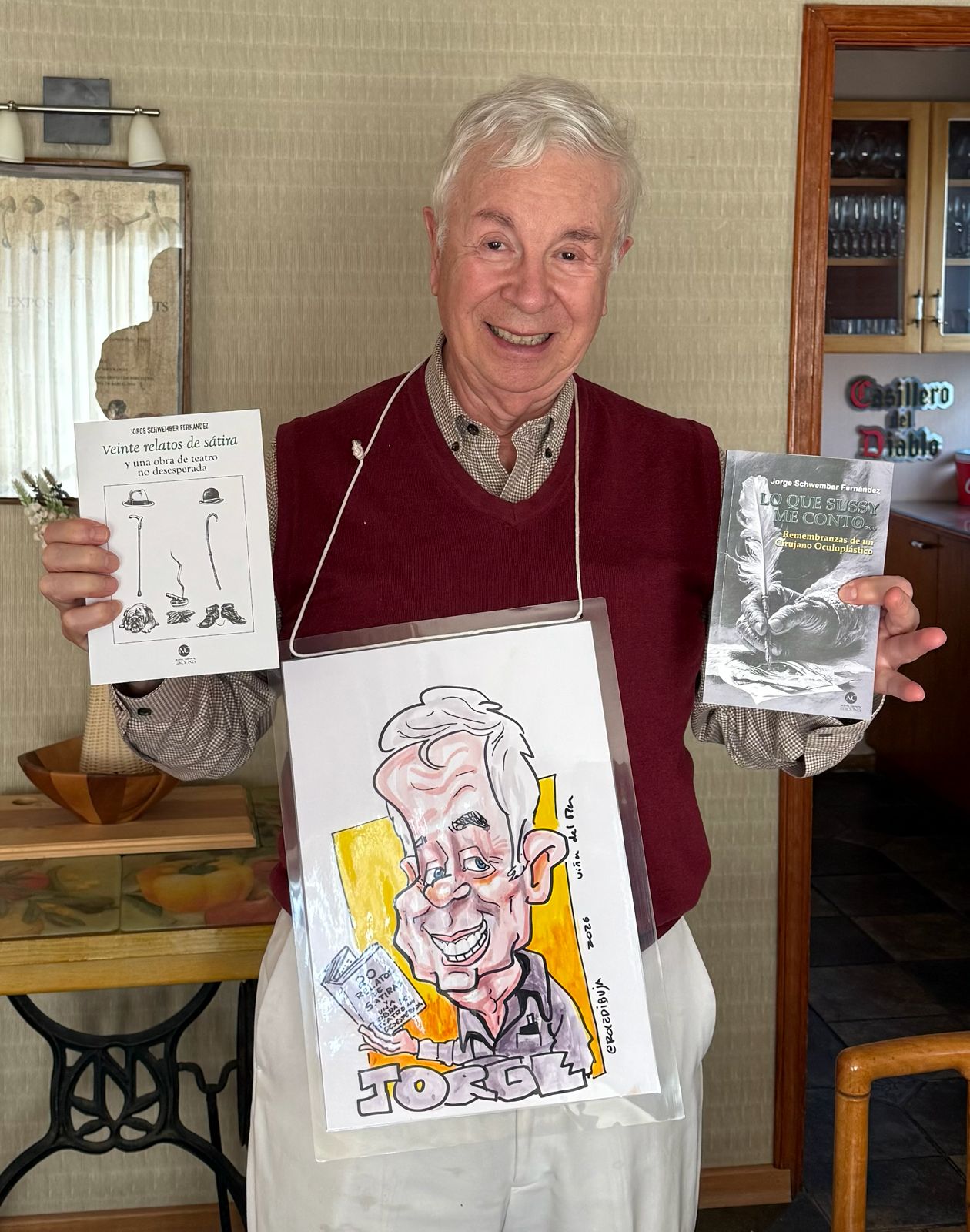 Jorge Schwember F sosteniendo sus libros y una caricatura